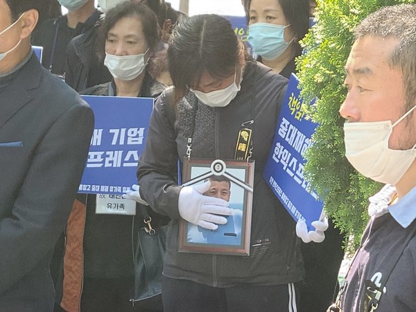 서울 서초동 한익스프레스 본사 앞에서 한 유가족이 영정사진을 쓰다듬고 있다. <사진 = 조유송 기자>