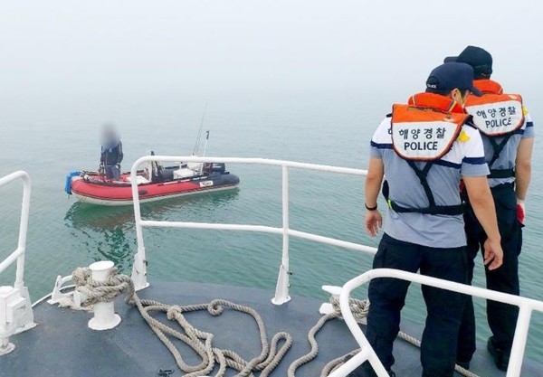 표류한 고무보트를 구조하고 있는 해경 모습 <사진 = 연합뉴스>