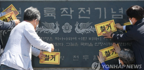 시민단체 회원들이 기념석비에 철거 스티커를 부착하고 있다.<연합뉴스>